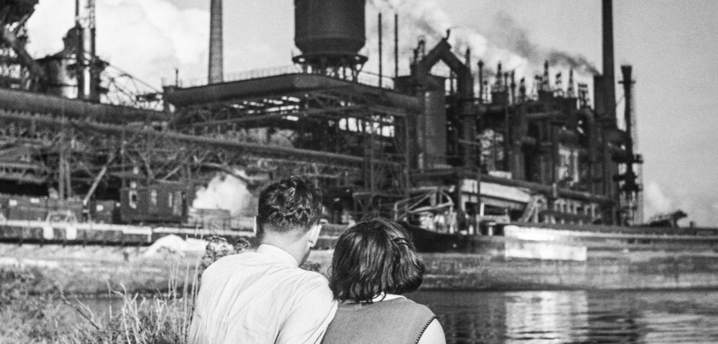 Couple looking at industrial plant by a river