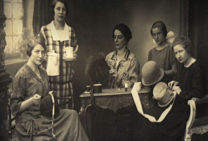Historische Schwarz-weiß-Zeichnung von fünf Frauen in einer Hut-Werkstatt