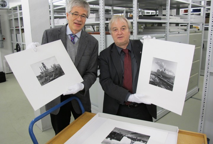 Zwei Herren zeigen historische Schwarzweiß-Fotografien