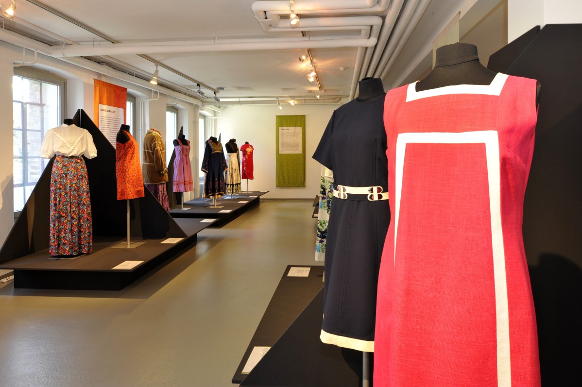 Blick in die Ausstellung, im Vordergrund ein rotes Kleid