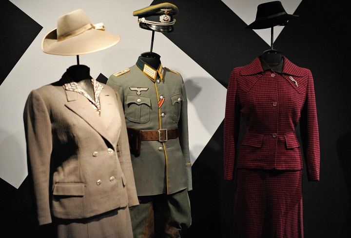 Eine Uniform und zwei Kostüme für Damen an Figurinen in der Ausstellung