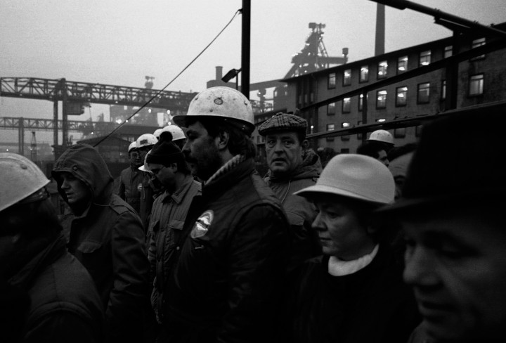 Schwarzweiß-Foto einer Gruppe Männer mit Helmen in einer Industrieanlage