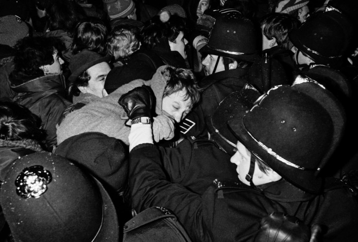 Schwarzweiß-Foto von drängelnden Männern mit Polizisten