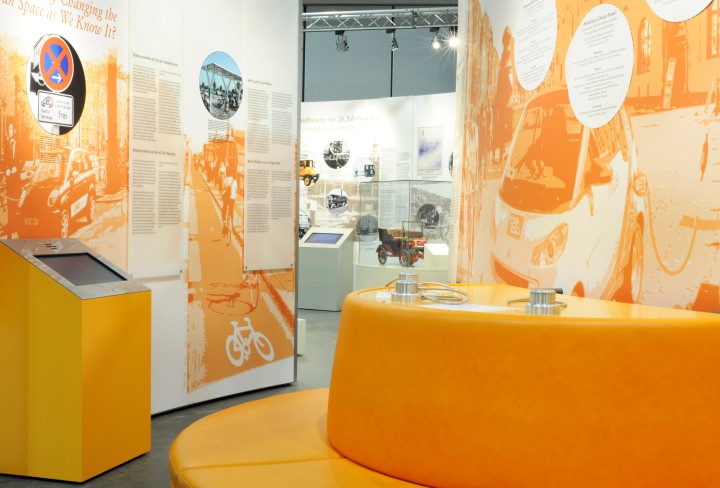 Blick auf runde Sitzgelegheit und Touch-Monitor in die Ausstellung