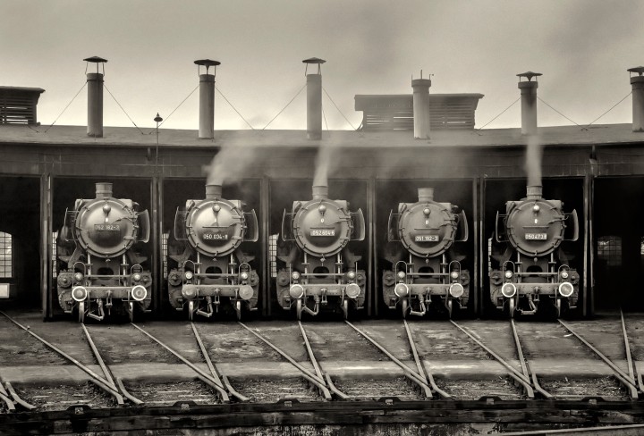 Schwarz-Weiß-Fotografie von fünf Loks in einem Bahnbetriebswerk