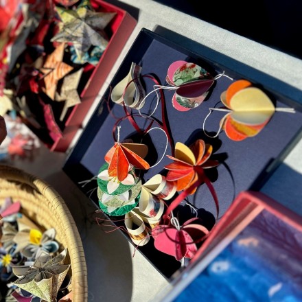 Aus Papier gefertigte Deko-Anhänger in Blumenform werden an einem Verkaufstisch präsentiert