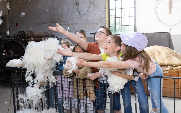 Mädchen und Jungen haben Spaß bei Hands-On-Angebot mit roher Wolle