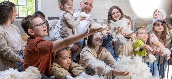 Besuchergruppe mit Erwachsenen und Kindern fangen lose Wolle auf