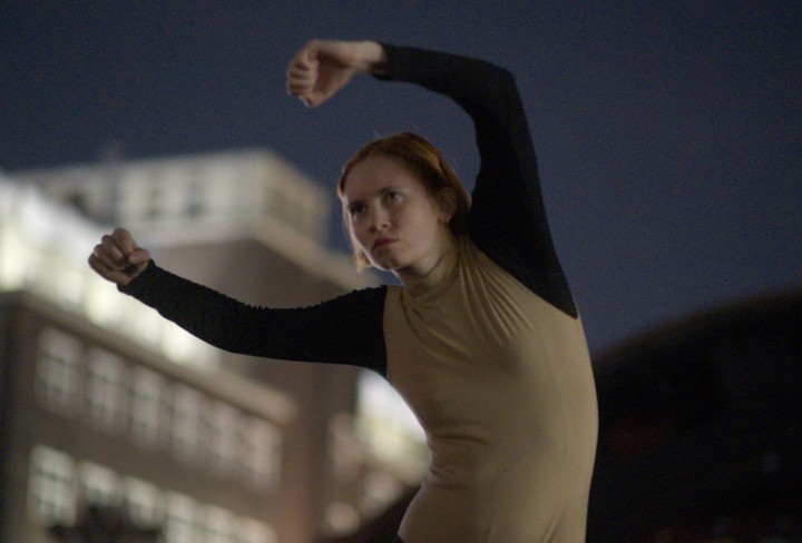 Tänzerin im Dunkeln vor einem beleuchteten Industriegebäude