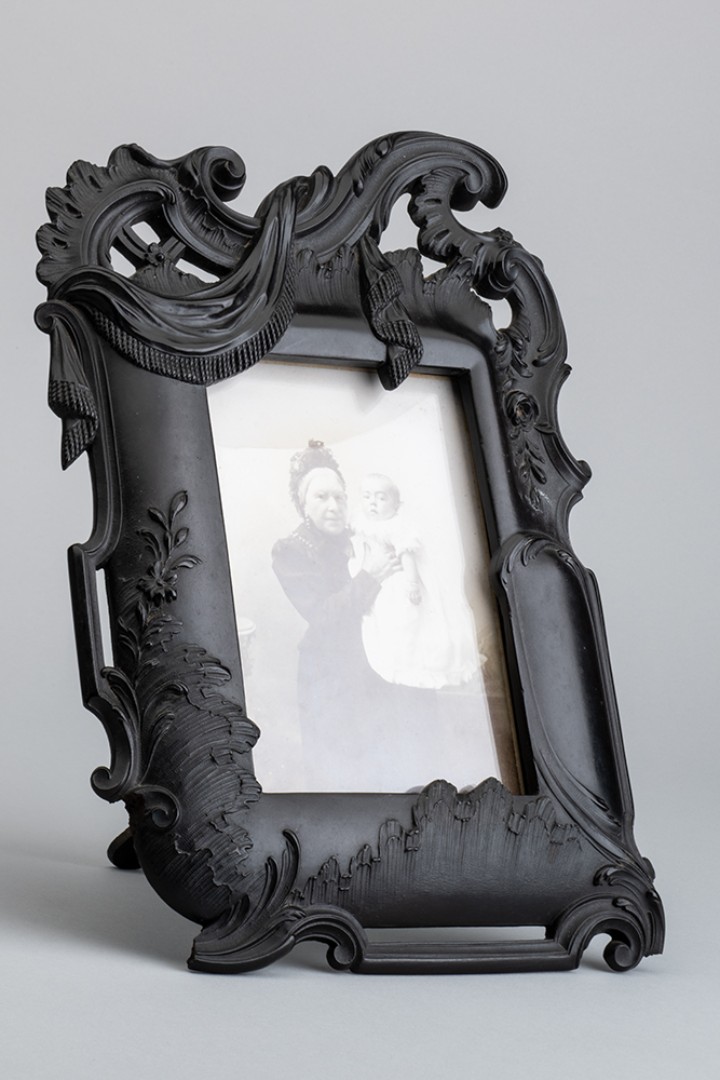 Schwarzer, kunstvoll gestalteter Kunststoffbilderrahmen mit Portrait einer älteren Dame mit Kind