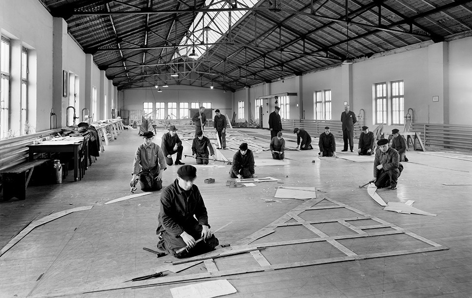 Historisches Schwarzweiß-Foto einer Fabrikhalle mit Arbeitern
