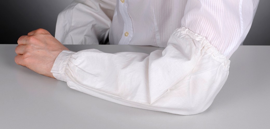 Detailansicht eines Armes mit einem weißen Hemd und einem Ärmelschoner