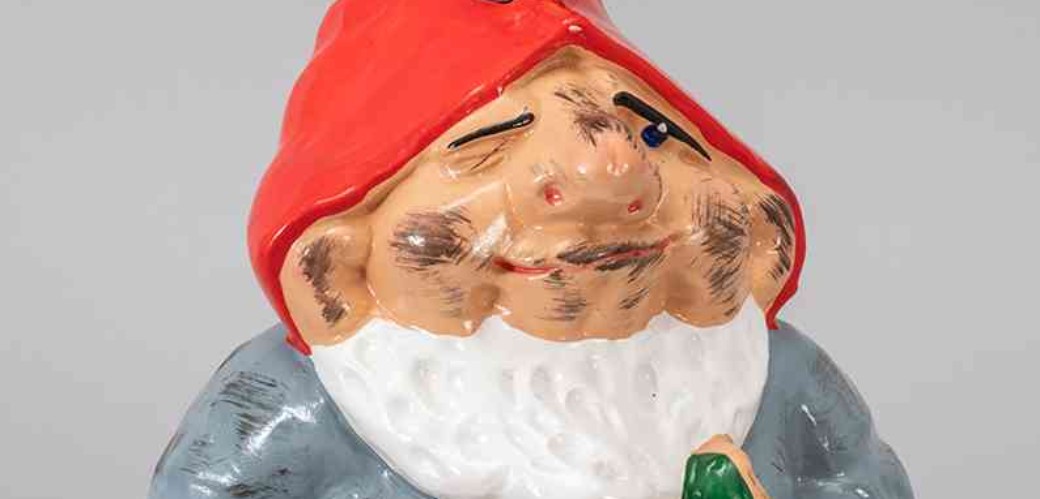 Gartenzwerg mit roter Mütze, einer Stirnlampe, weißem Bart. Er ist schmutzig und trägt eine blaue Uniform. 
