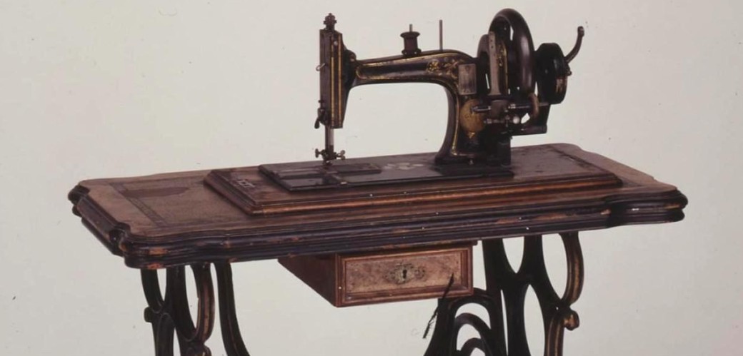 Nähmaschine auf gusseisernem Gestell mit Trittplatte, Schwungantrieb und Arbeitsplatte