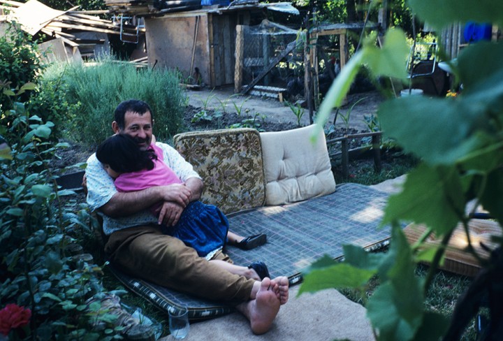Mann sitzt mit Kind auf dem Schoß in einem Garten