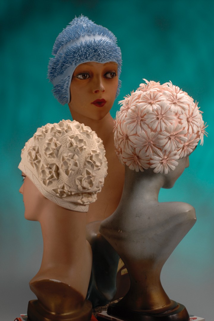 Three bathing caps with attached flower-like patterns