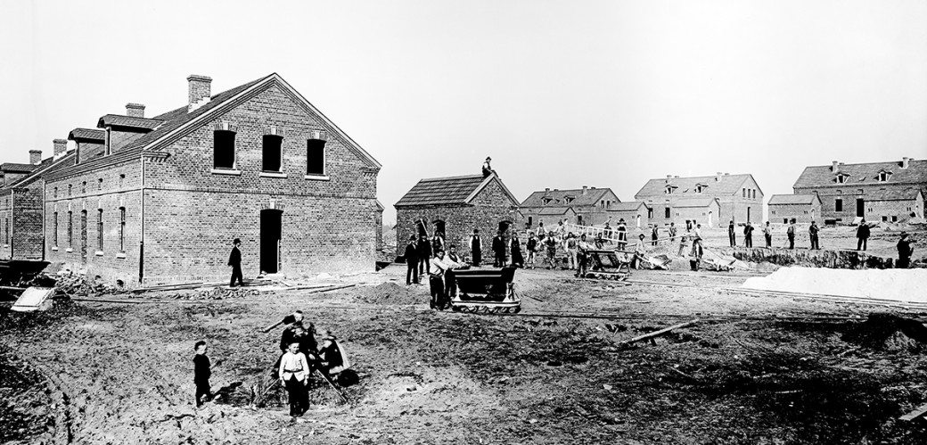Männer beim Arbeiten, im Hintergrund einige Häuser