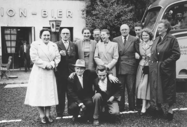 Schwarz-Weiß Foto von Männern und Frauen die vor einem Ausfluglokal stehen