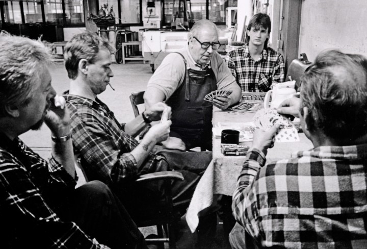 Schwarz-Weiß Foto von Männern die an einem Tisch sitzen und Karten spielen