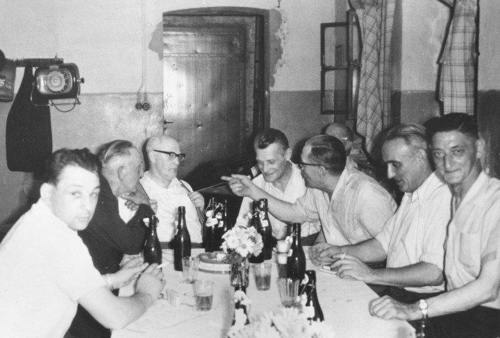 Schwarz-Weiß Foto von Männern die an einem Tisch sitzen und etwas trinken
