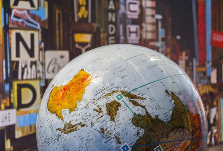 Großer Globus, im Hintergrund ein Foto einer beleuchteten Einkaufsstraße