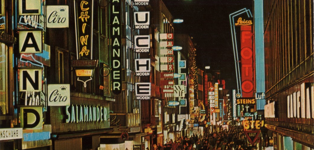 Historisches Foto einer beleuchteten Einkaufsstraße mit vielen Menschen