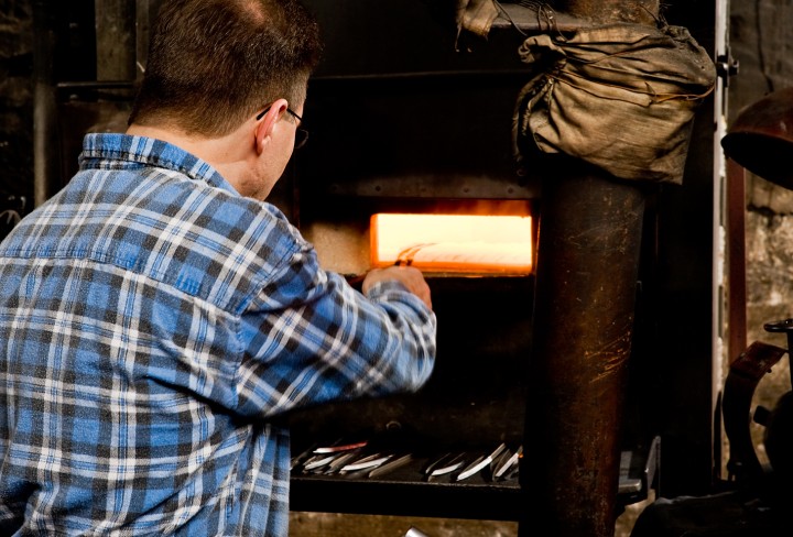 Museum blacksmith pushes a workpiece into the furnace