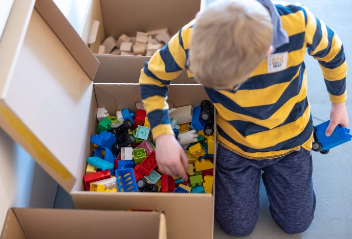 Ein Junge wühlt in einer Kiste mit Bausteinen