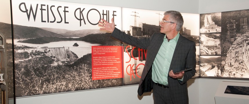 Ein Herr erklärt etwas an einem Banner in der Ausstellung