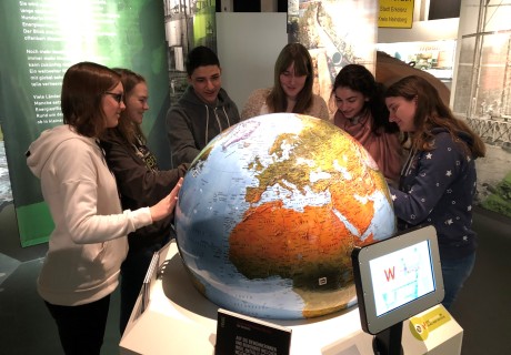 Mehrere Jugendliche betrachten einen großen Globus in der Ausstellung