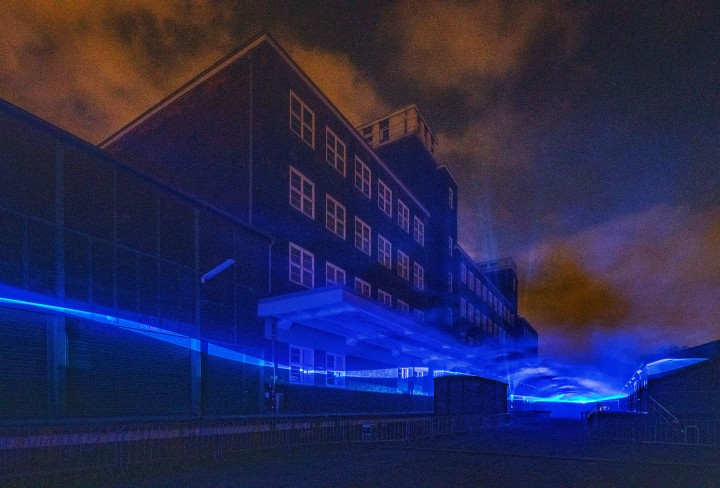 Historical factory building illuminated with floating wave like light