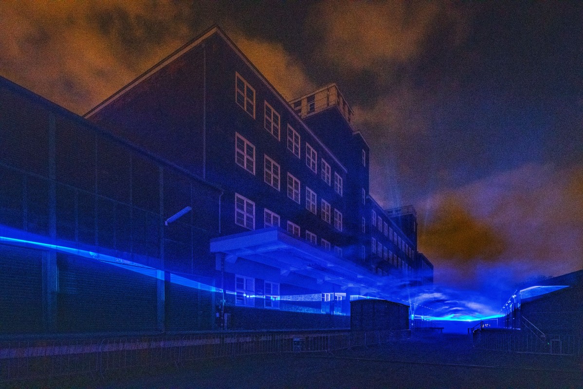 Mit schwebendem wellenartigem Licht illuminiertes historisches Fabrikgebäude