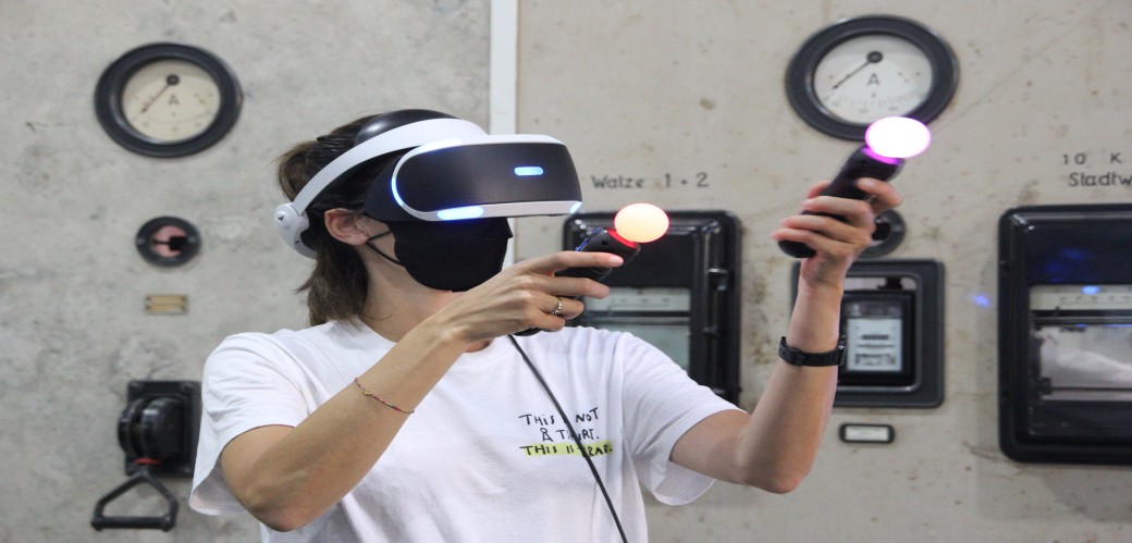 Eine junge Frau im Raum mit einer VR-Brille und Controllern.