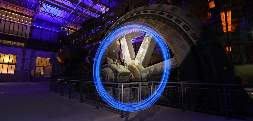 Ein hell leuchtender Kreis aus Licht vor einem großen Industrierad
