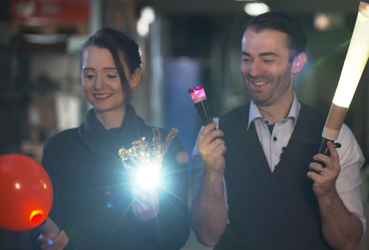 Ein Mann und eine Frau halten leuchtende Gegenstände in ihren Händen