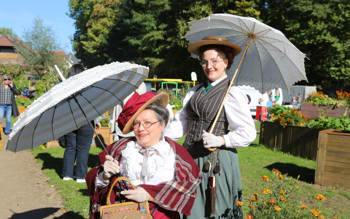 Zwei Frauen in historischer Kleidung, die Sonnenschirme halten, auf dem Antony-Fest.