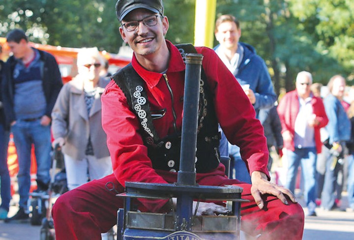 Lokführe in Kostüm mit Hut auf kleiner Lok