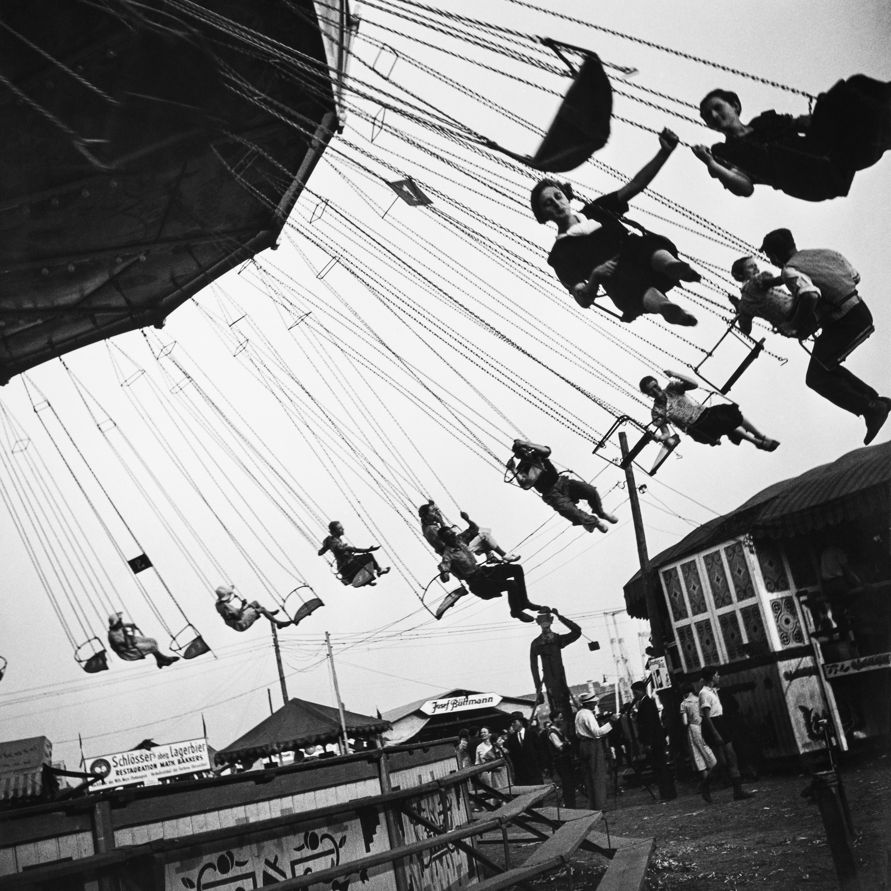 Black and white picture of a moving chain carousel at a funfair. 