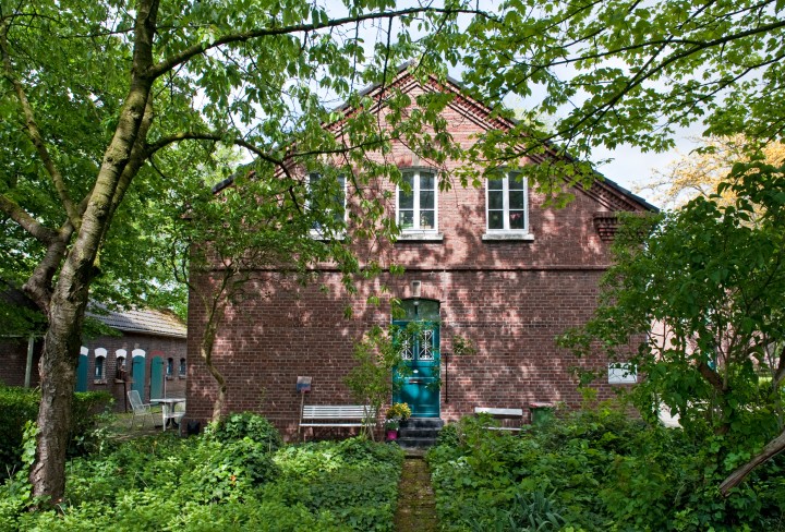 Aufnahme eines Hauses der Arbeitersiedlung Eisenheim mit zwei weißen Bänken.