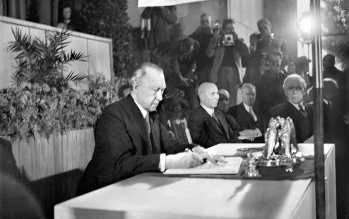 Historisches Schwarz-Weiß-Foto von Konrad Adenauer an einem Tisch beim Unterschreiben des Grundgesetzes.