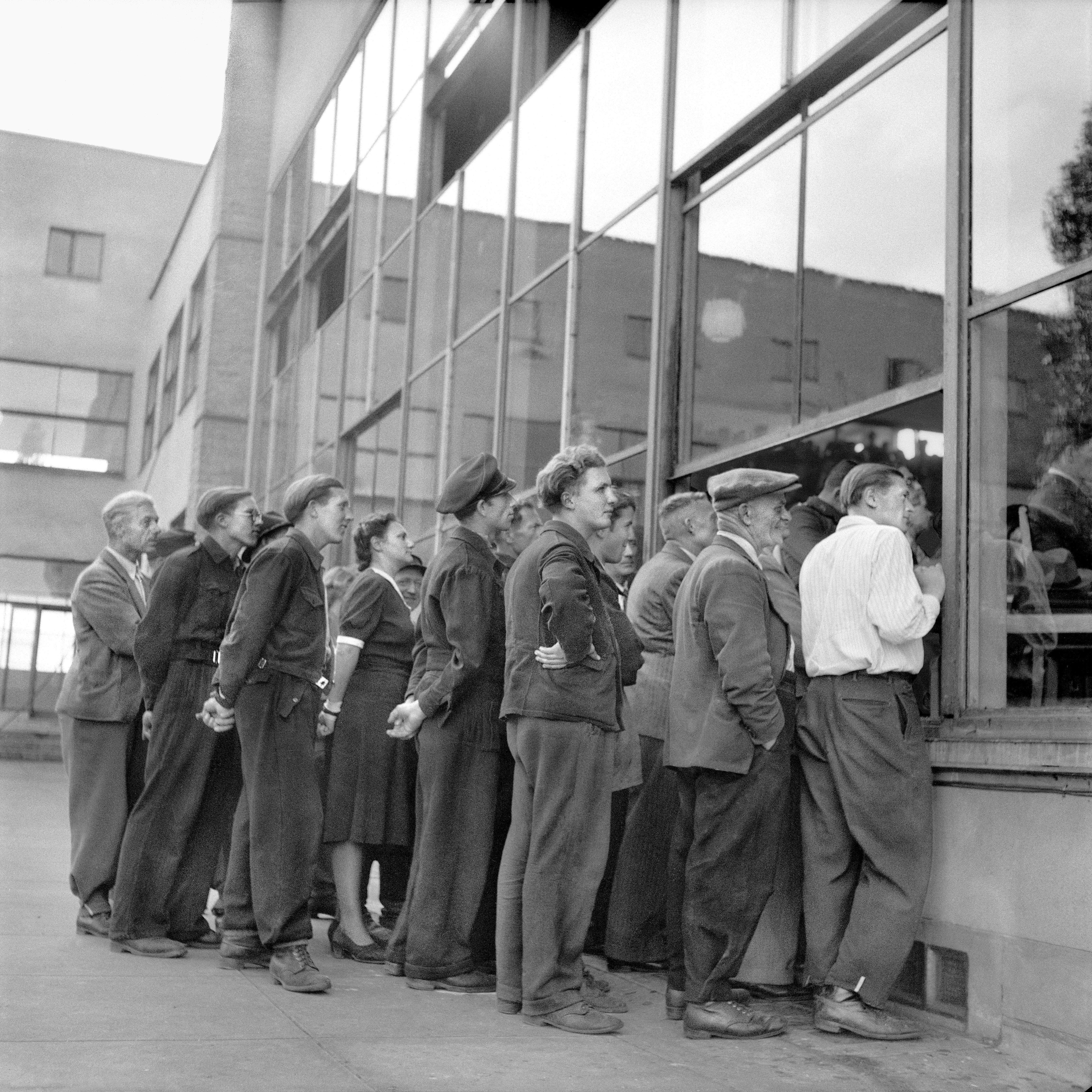 Gruppe von Menschen drängen sich vor einer Fensterfront, um hereinzuschauen.