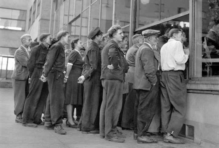 Gruppe von Menschen drängen sich vor einer Fensterfront, um hereinzuschauen.