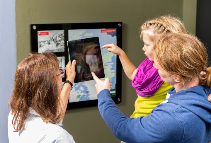 Zwei Erwachsene und ein Kind erkunden das Museum mithilfe der Ausstellungs-App
