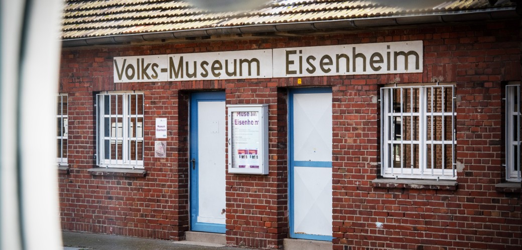 Fassade des Museums Eisenheim durch einen Zaun hindurch fotografiert