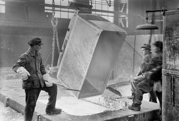 Historisches Schwarzweiß-Foto von Arbeitern, die etwas Heißes abkippen