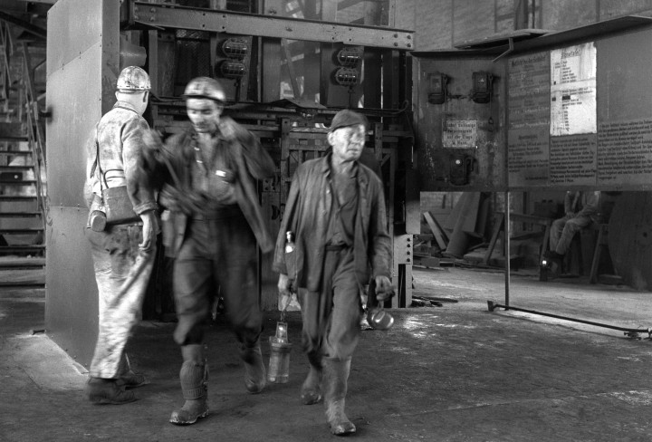 Eine schwarz-weiß Fotografie von drei Männer auf dem Weg aus dem Grubenaufzug auf der Zeche Alstaden.