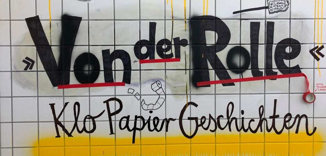 Graffitti mit der Aufschrift "Von der Rolle - KloPapierGeschichten" auf weißen Fliesen