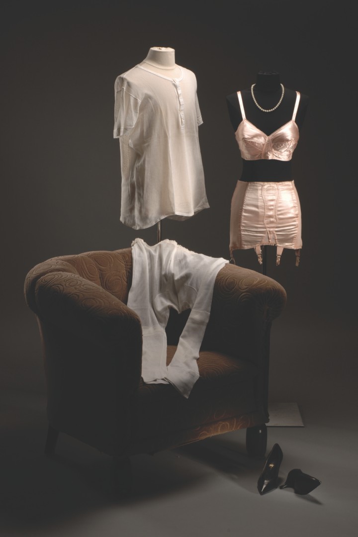 Damen- und Herrenunterwäsche der 1950er Jahre auf Figurinen hinter einem Sessel