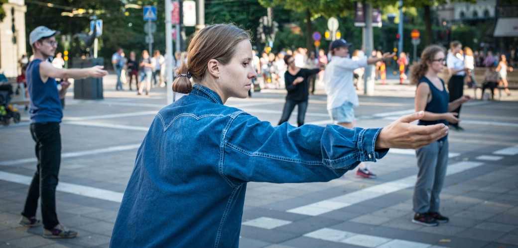 Eine Gruppe performt eine künstlerische Choreografie auf einer Straßenkreuzung.