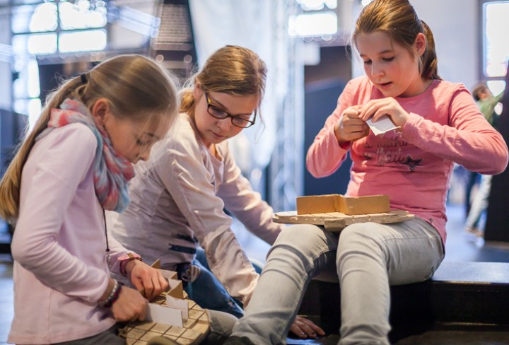 3 Kinder basteln Schuhe aus Holz und Karton.